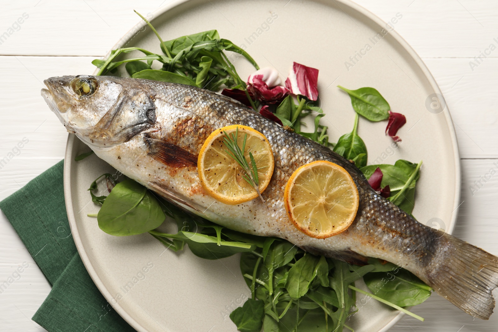 Photo of Baked fish with spinach and lemon on white wooden table, top view