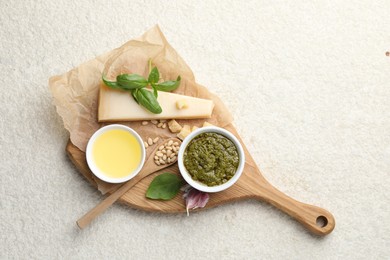 Tasty pesto sauce, basil, pine nuts, garlic, oil and cheese on light grey table, top view. Space for text