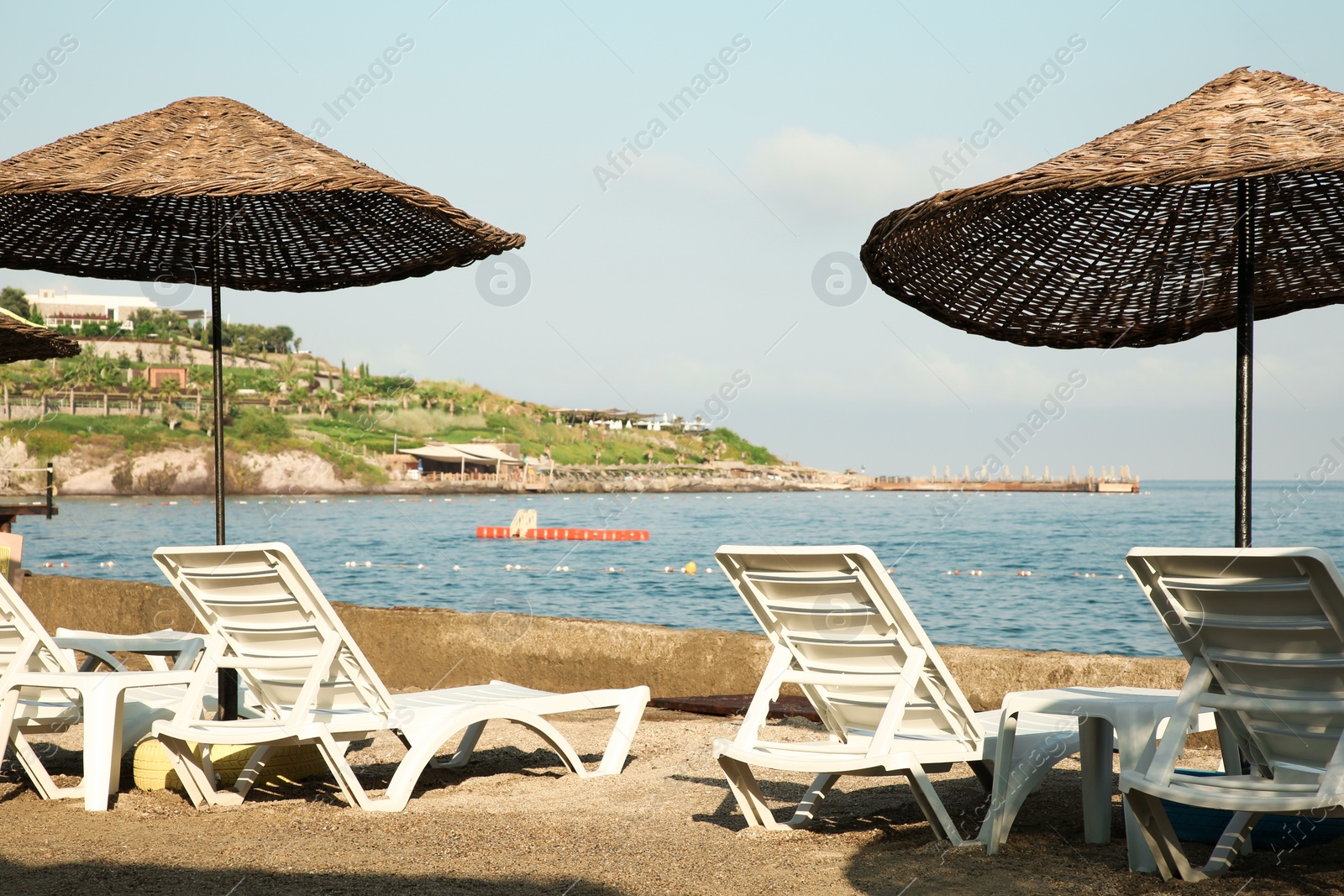 Photo of Lounge chairs and beach umbrellas on sea shore