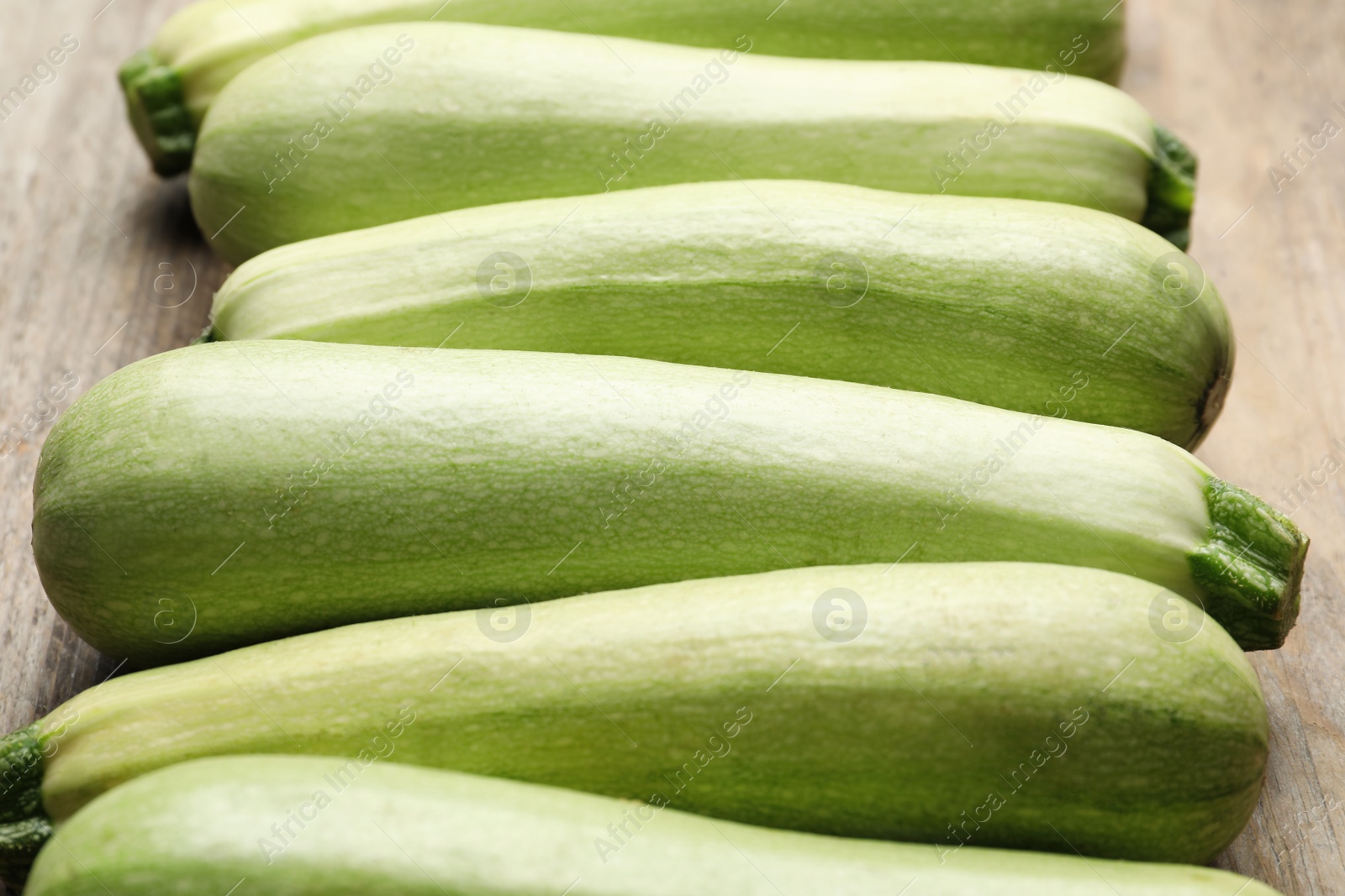 Photo of Raw green zucchinis on wooden table, closeup