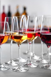 Glasses with different wines on table against blurred background