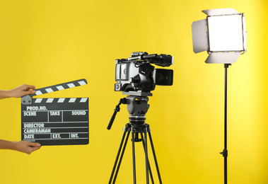 Woman with clapperboard near video camera in studio, closeup