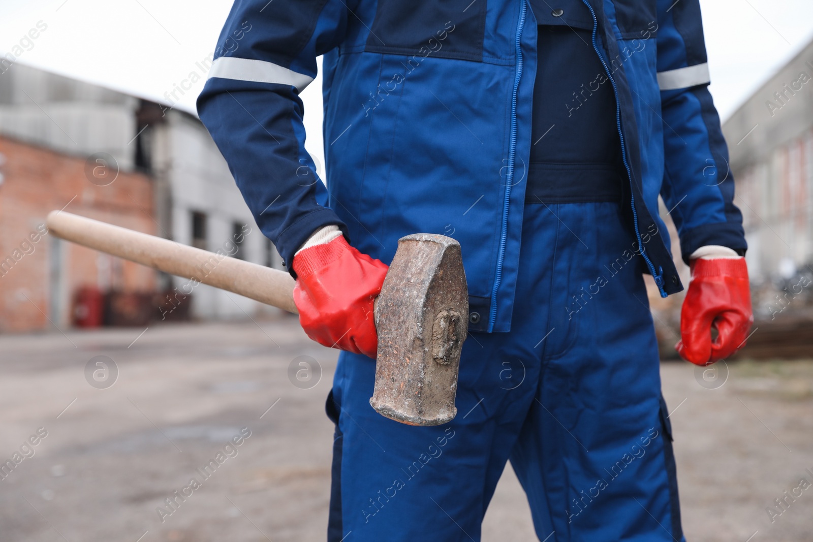 Photo of Man in uniform with sledgehammer outdoors, closeup