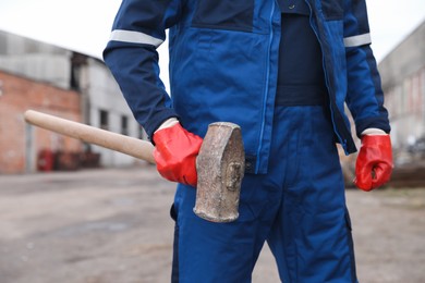 Photo of Man in uniform with sledgehammer outdoors, closeup