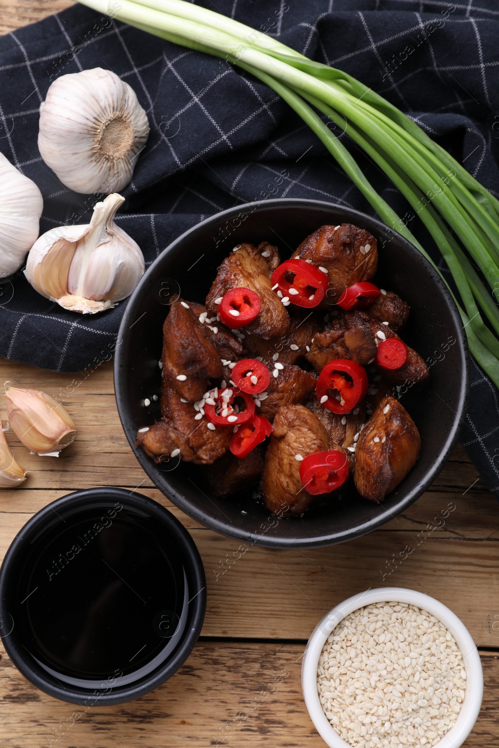 Photo of Tasty roasted meat, soy sauce and products on wooden table, flat lay