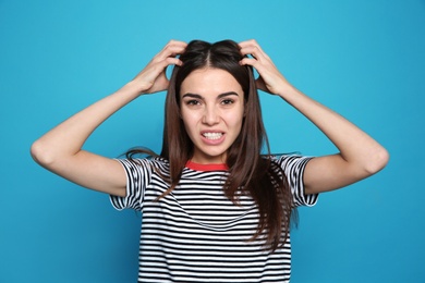 Photo of Young woman scratching head on color background. Annoying itch