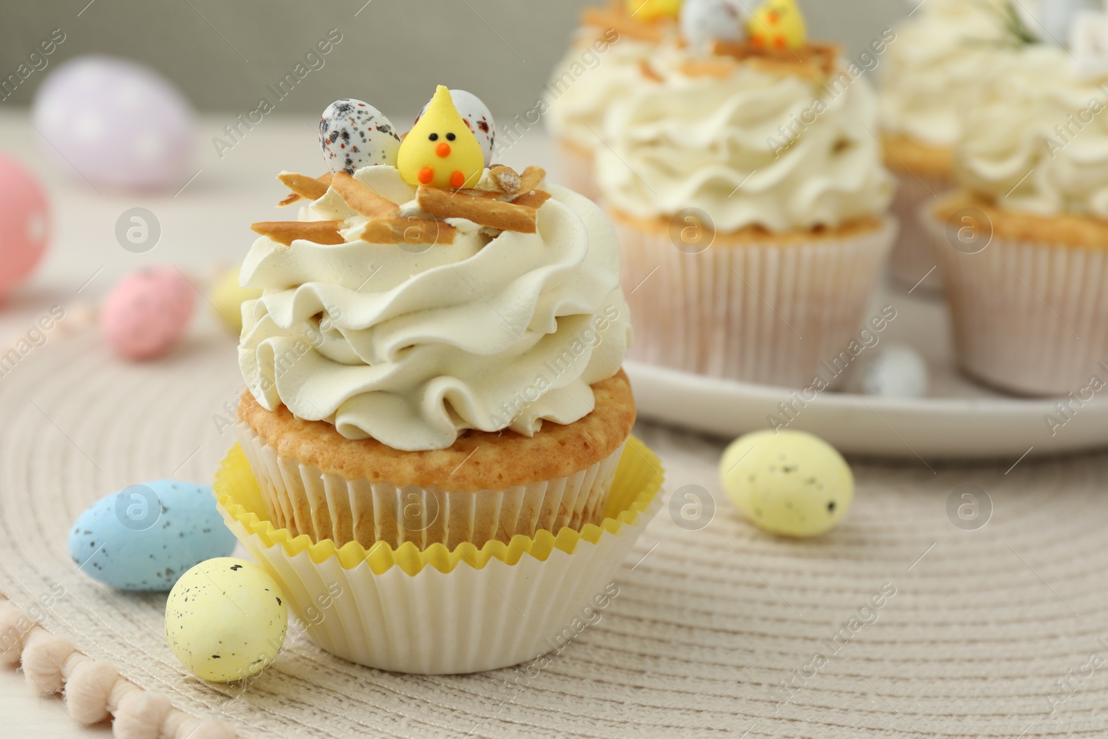 Photo of Tasty Easter cupcakes with vanilla cream and candies on table, closeup