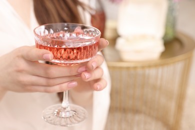 Woman holding glass of delicious wine indoors, closeup. Space for text