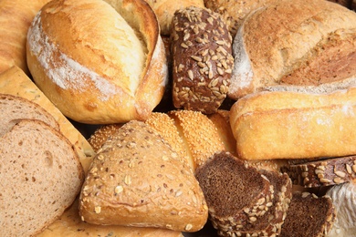 Photo of Different kinds of bread as background, closeup
