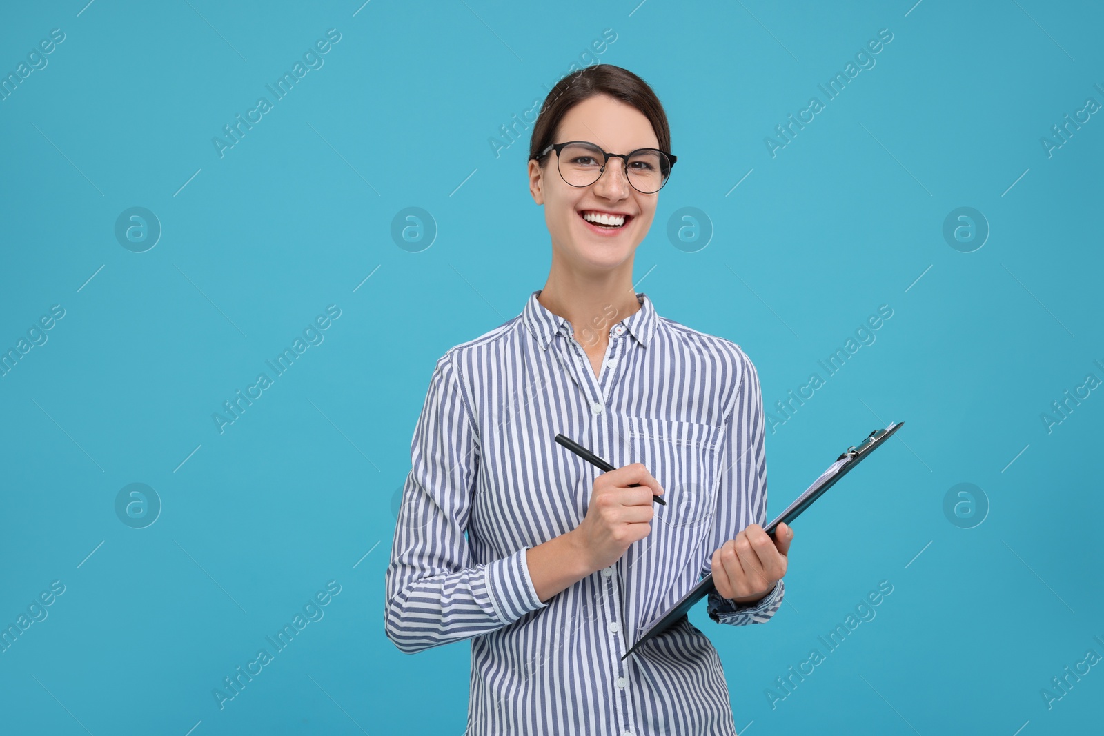 Photo of Happy secretary with clipboard and pen on light blue background