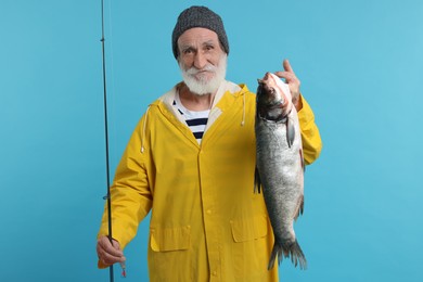 Photo of Fisherman with rod and catch on light blue background