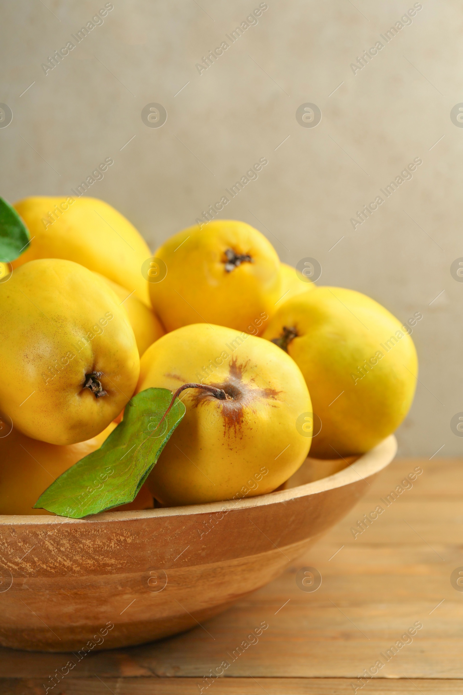 Photo of Tasty ripe quince fruits in bowl on wooden table, closeup