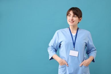 Portrait of smiling medical assistant on light blue background. Space for text