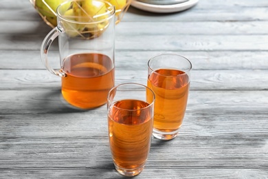 Photo of Glasses and jug of apple juice on wooden table