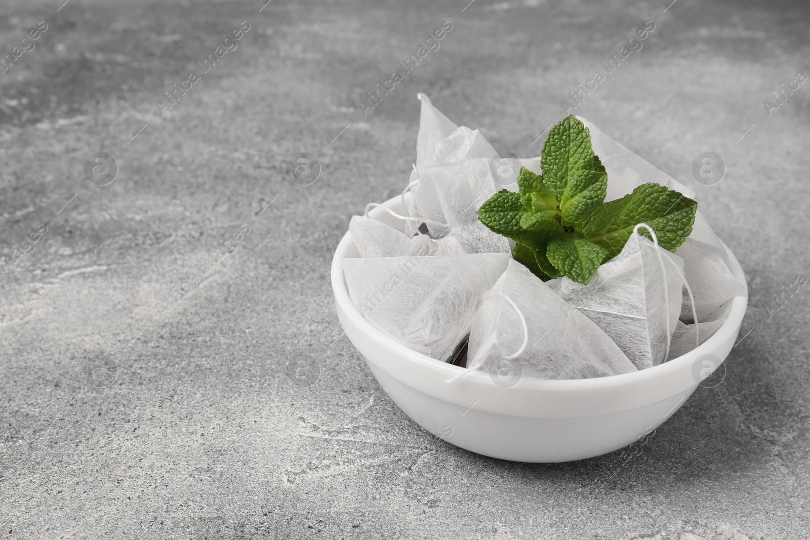 Photo of Tea bags and mint on light grey table. Space for text