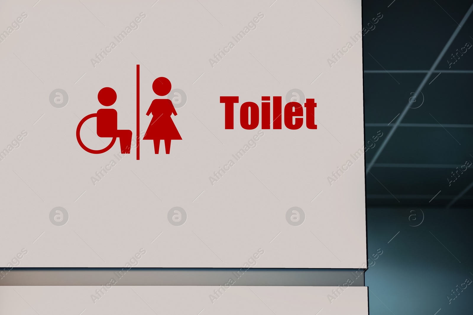 Image of Red public toilet sign on white wall indoors