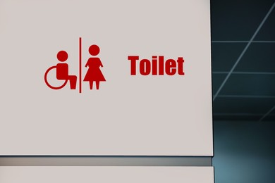 Image of Red public toilet sign on white wall indoors