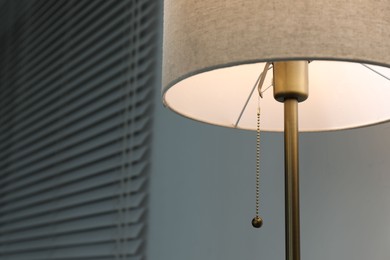 Stylish lamp near light wall, closeup. Space for text