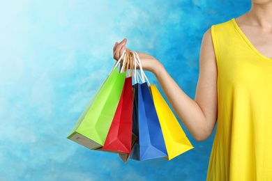 Photo of Woman holding paper shopping bags on color background