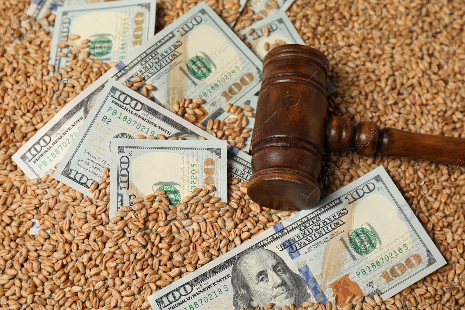 Photo of Dollar banknotes and wooden gavel on wheat grains, closeup. Agricultural business