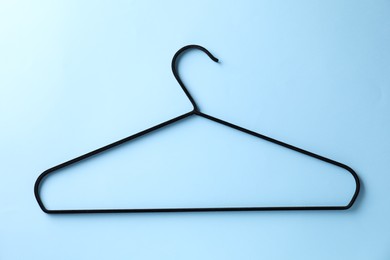 One black hanger on light blue background, top view
