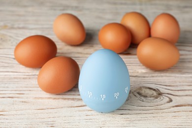 Photo of Kitchen timer and eggs on white wooden table