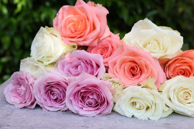 Photo of Beautiful bouquet of roses on light grey table outdoors, closeup