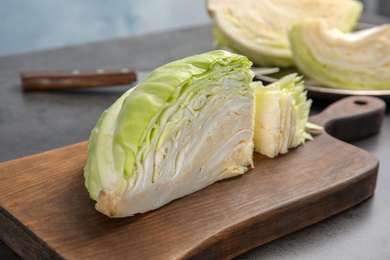 Photo of Wooden board with cut cabbage on table