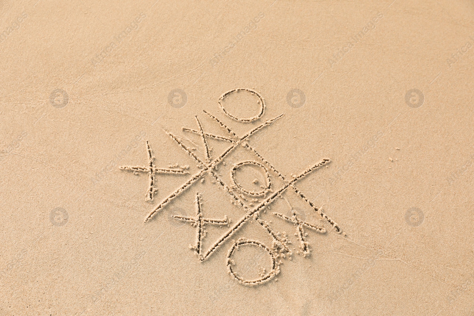 Photo of Tic tac toe game drawn on sandy beach, above view