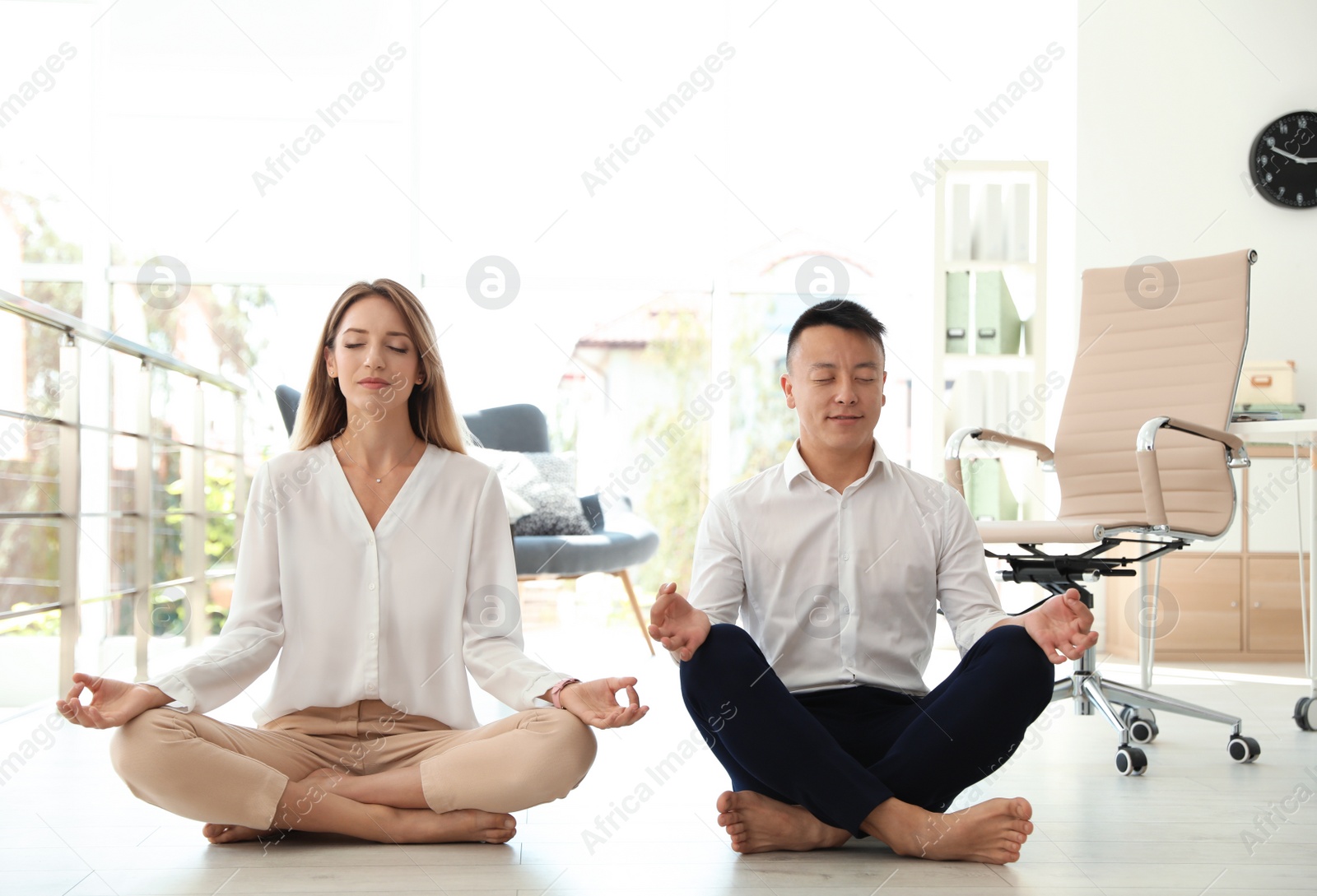 Photo of Young colleagues doing yoga in office. Workplace fitness