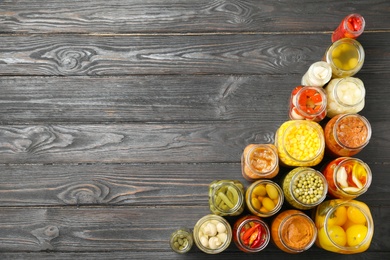 Photo of Jars of pickled vegetables on black wooden table, flat lay. Space for text