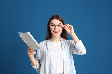 Photo of Young woman with book on blue background