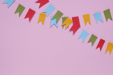 Colorful bunting flags on pink background, flat lay. Space for text