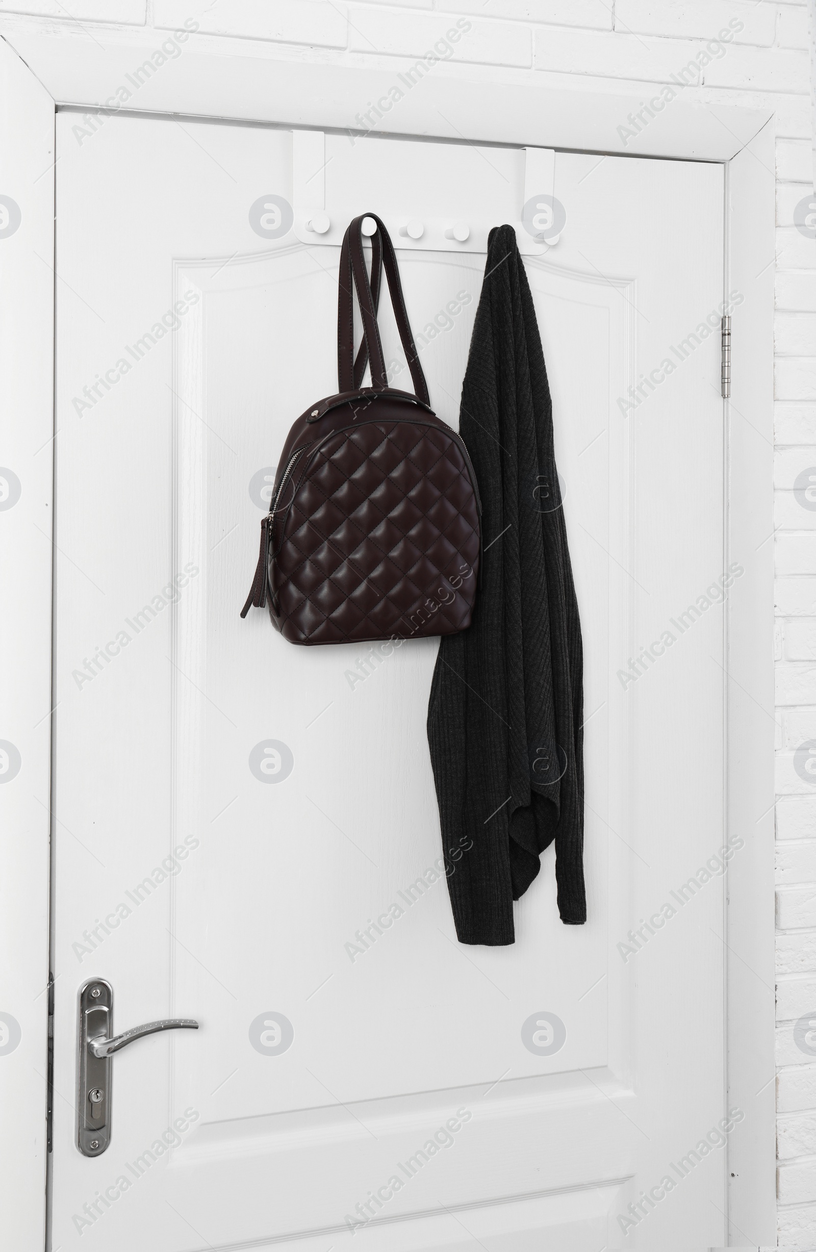 Photo of Backpack and clothing hanging on white wooden door