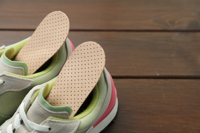 Photo of Orthopedic insoles in shoes on floor, closeup. Space for text
