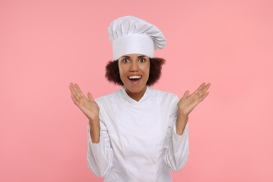 Photo of Portrait of emotional female chef in uniform on pink background