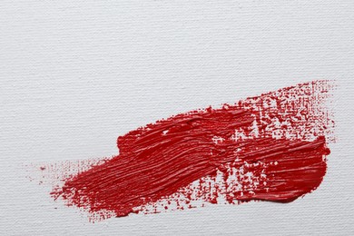 Photo of Stroke of red paint on white canvas, top view. Space for text