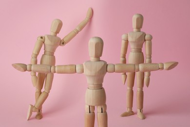 Image of Wooden human models in different poses on pink background