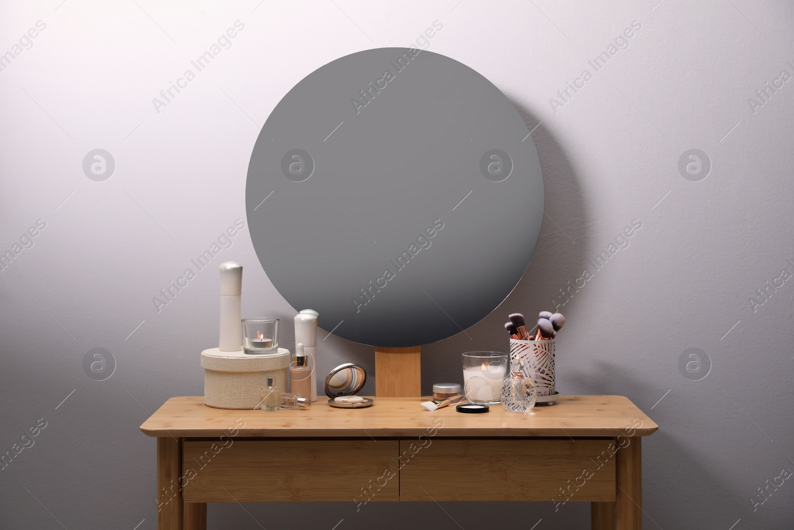 Photo of Stylish dressing table with cosmetics, mirror and accessories near white wall