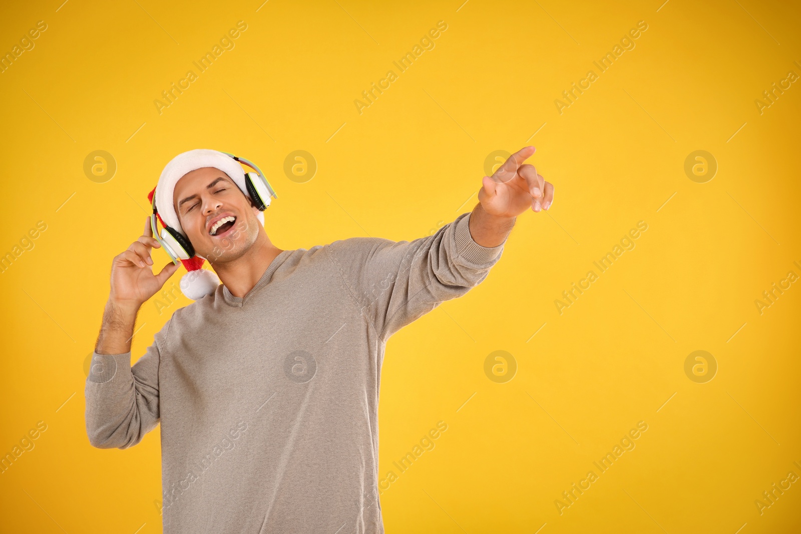 Photo of Emotional man with headphones on yellow background. Christmas music