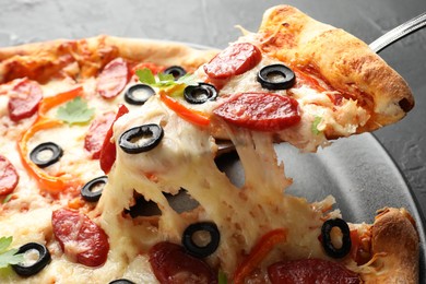 Photo of Taking piece of tasty pizza at table, closeup