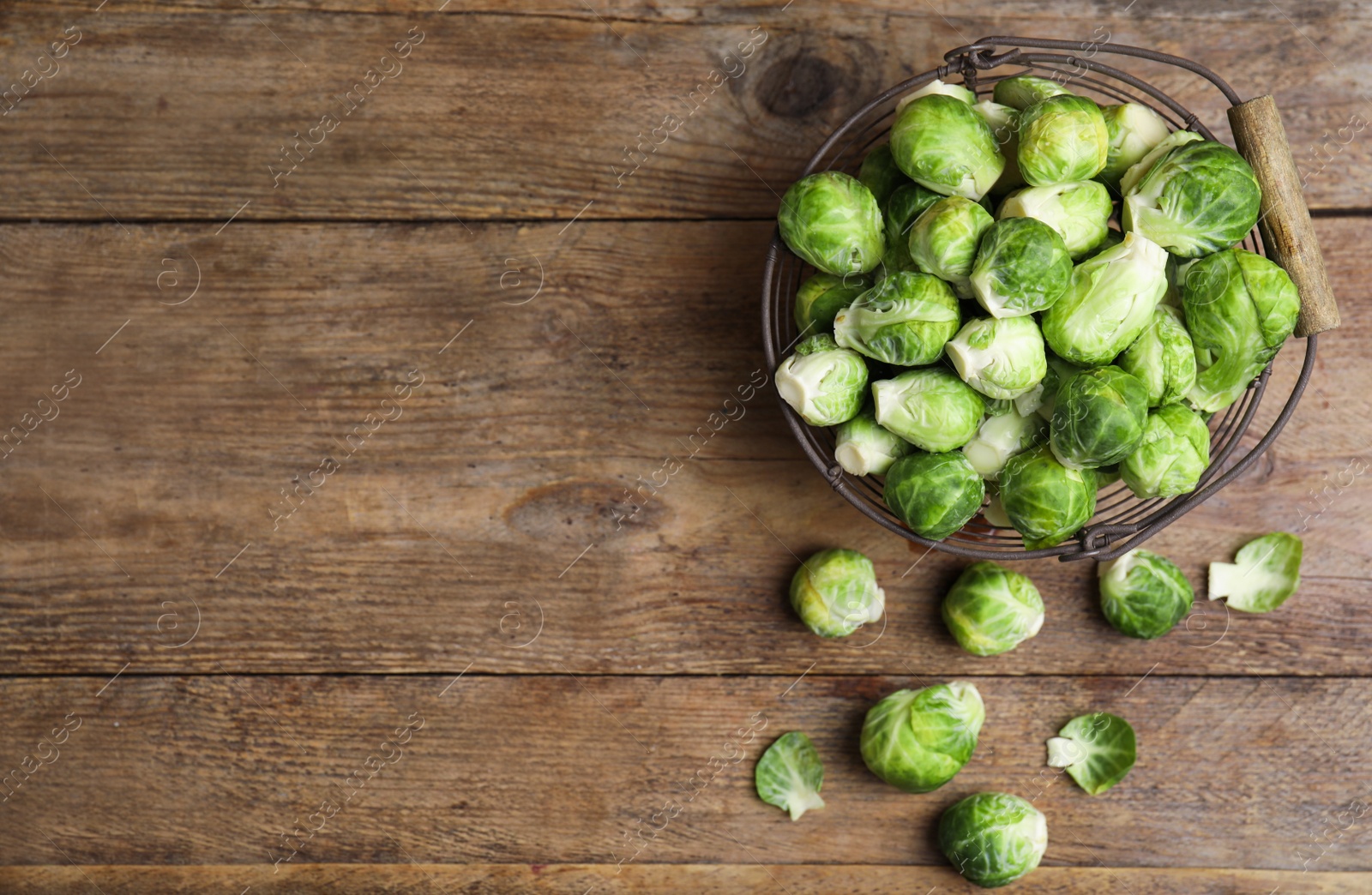 Photo of Fresh Brussels sprouts on wooden table, flat lay. Space for text