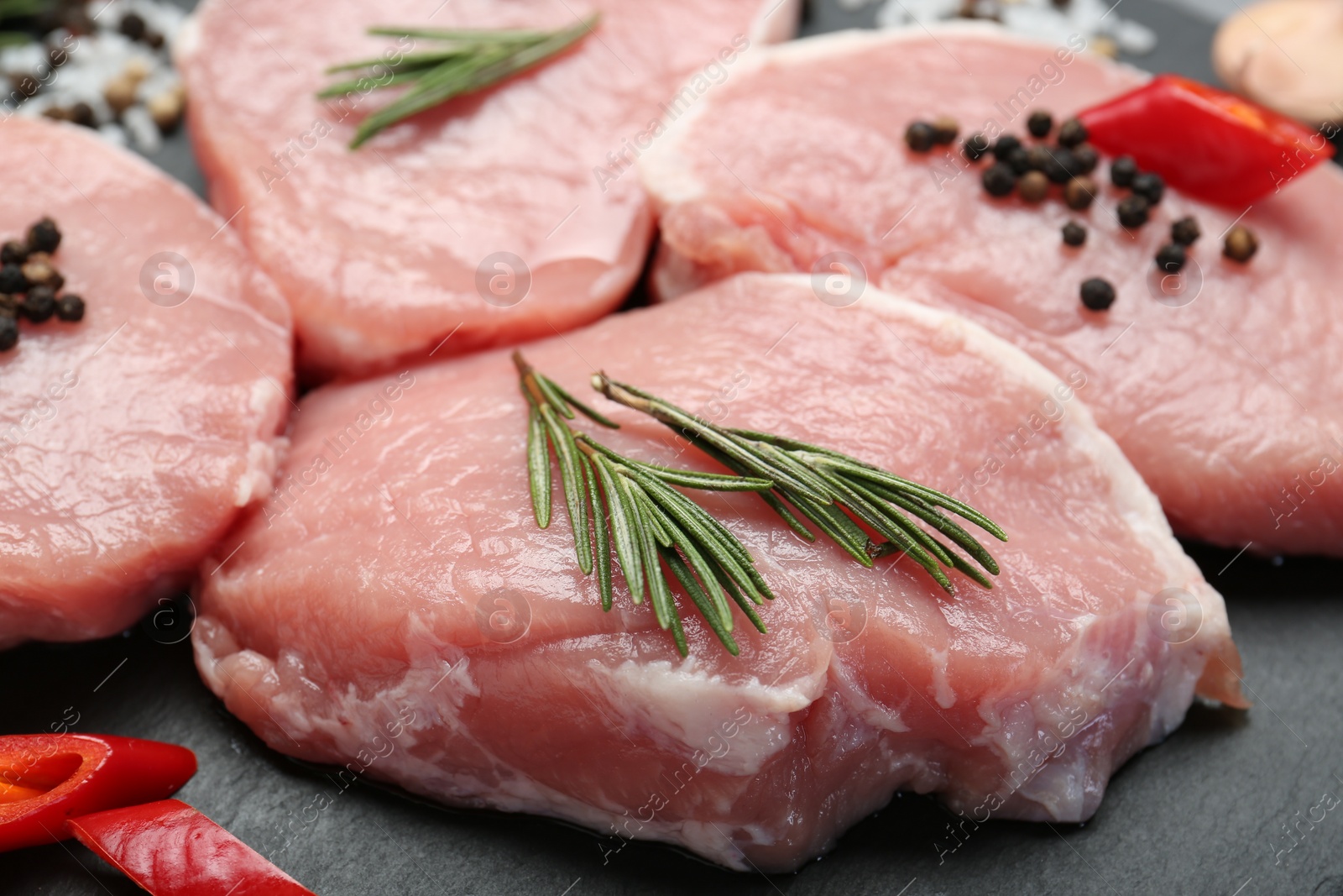 Photo of Pieces of raw pork meat, chili pepper and spices on board, closeup