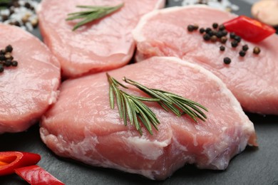 Photo of Pieces of raw pork meat, chili pepper and spices on board, closeup