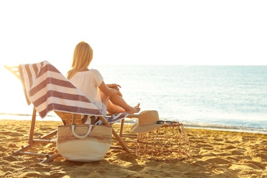 Woman relaxing on deck chair at sandy beach. Summer vacation