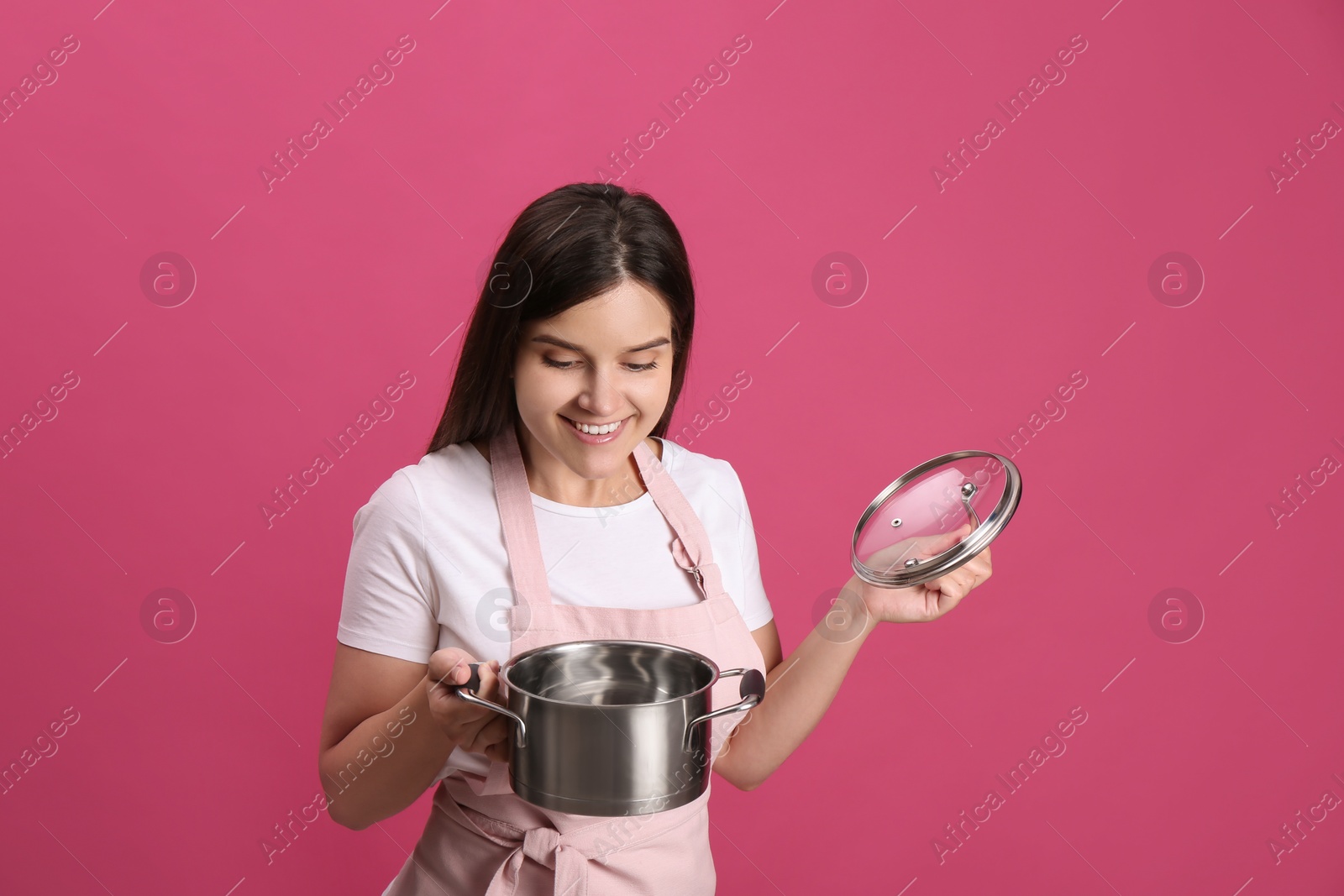 Photo of Happy young woman with cooking pot on pink background