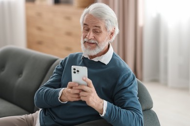 Photo of Portrait of happy grandpa using smartphone indoors