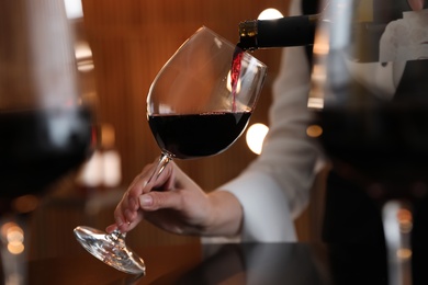 Photo of Waitress pouring wine into glass in restaurant, closeup