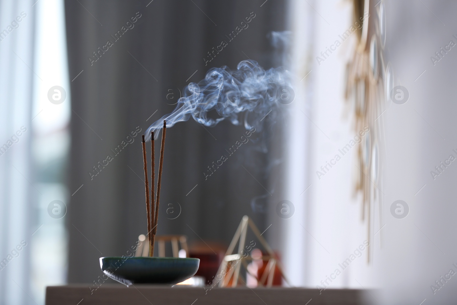 Photo of Incense sticks smoldering on table indoors, space for text