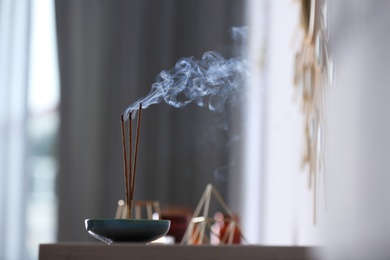 Incense sticks smoldering on table indoors, space for text